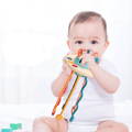 A baby holding and chewing a Montessori pulling toy made out of silicone. 