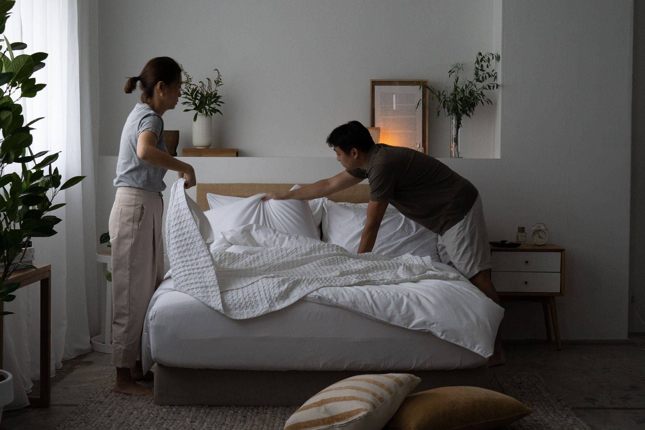 Couples tidying up the bed